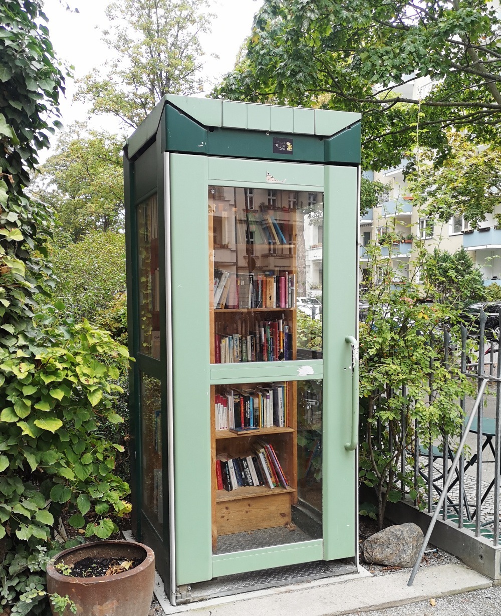 Donating books in a public bookcase in a phone booth in Berlin.