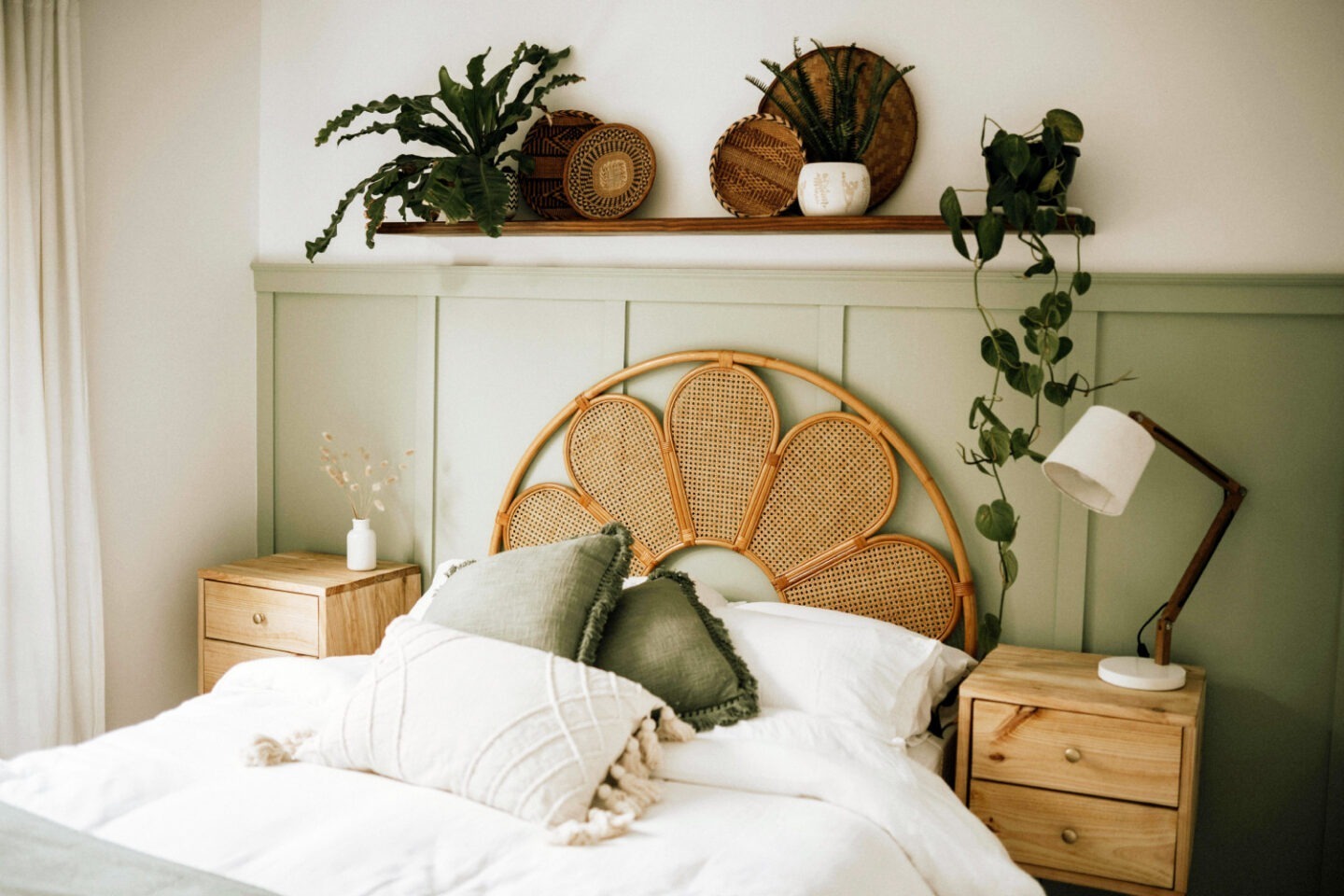 Ein aufgeräumtes Schlafzimmer mit grüner Wand und Pflanzen